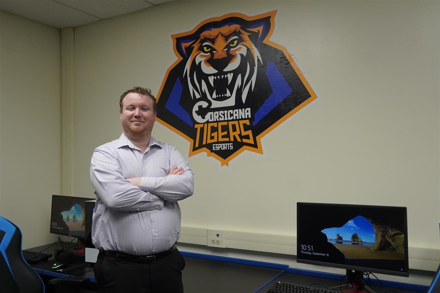 Groce standing in front of a Tiger logo and computers 